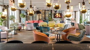 A modern lounge area with various seating options, including sofas and chairs, and decorative hanging light fixtures.