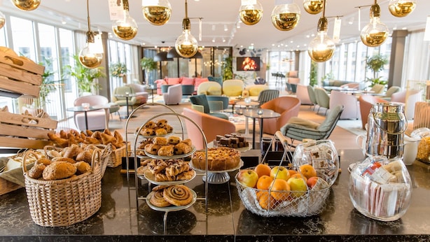 A well-lit room with a variety of baked goods displayed on a counter, including bread, pastries, and cakes.