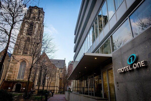 A building with a clock tower and a modern structure labeled 'Motel One'.