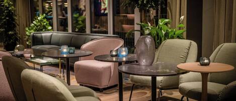 Een moderne lounge met lederen banken en fauteuils, ronde tafels en decoratieve vazen.