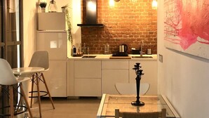 Una cocina moderna con pared de ladrillo, armarios blancos y un área de comedor con mesa y sillas.