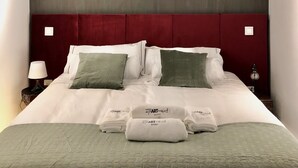Una habitación de hotel con una cama grande, un cabecero rojo y una colcha verde.