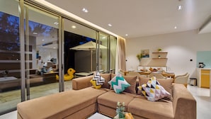 Ein modernes Wohnzimmer mit einem Ecksofa, einem Essbereich und einer Küche im Hintergrund.