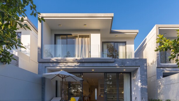 Ein modernes, zweistöckiges Haus mit Swimmingpool, Außenmöbeln und einer überdachten Terrasse.