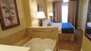 Een hotelkamer met een badkuip, een bed, een bureau en een badkamer met een handdoekhouder.