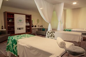 A spa room with two massage tables, a reception desk, and a wall-mounted display. - Beach Class Muro Alto Resort - New Time (Ipojuca)
