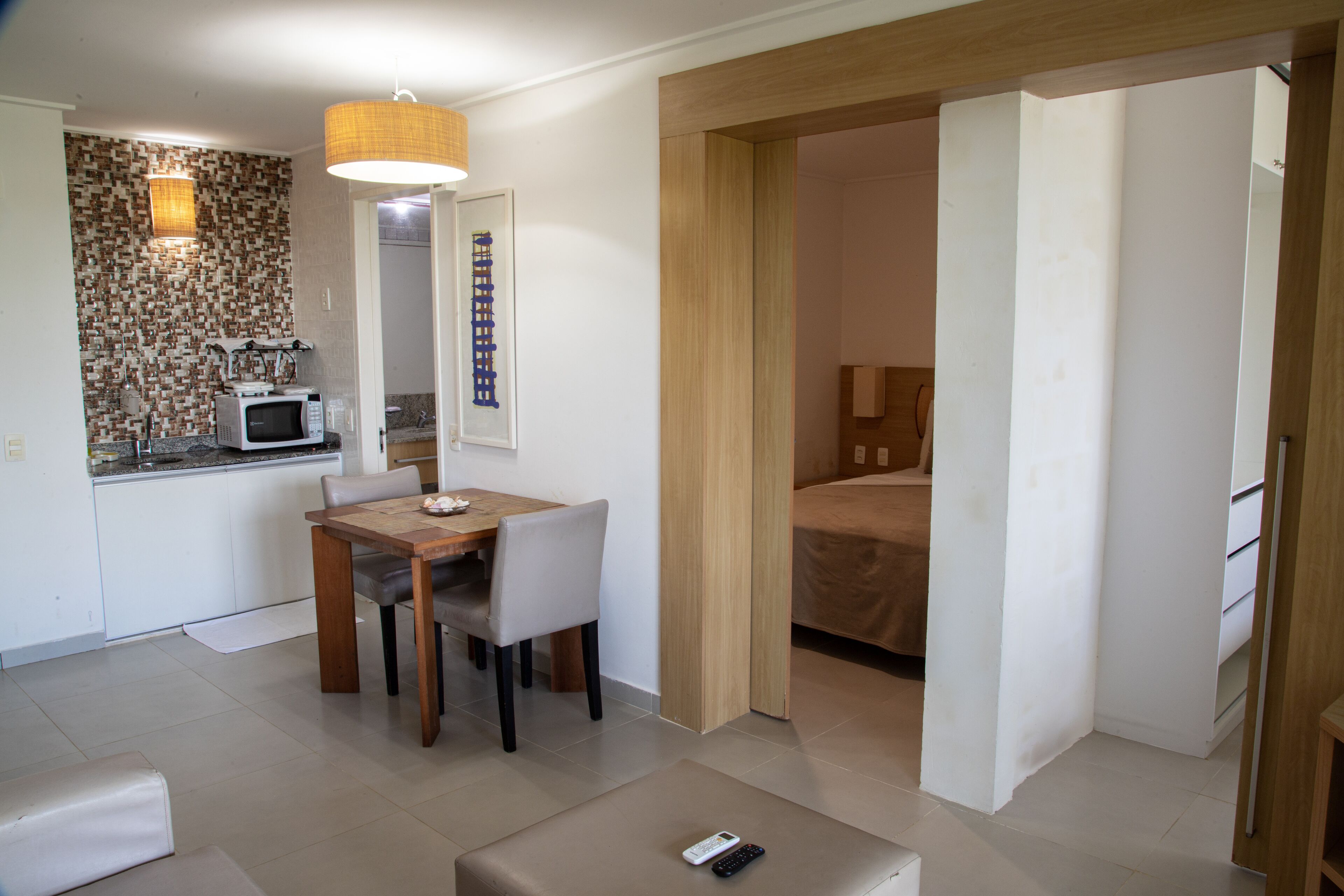 Een compacte hotelkamer met een kitchenette, een eethoek en een bed.