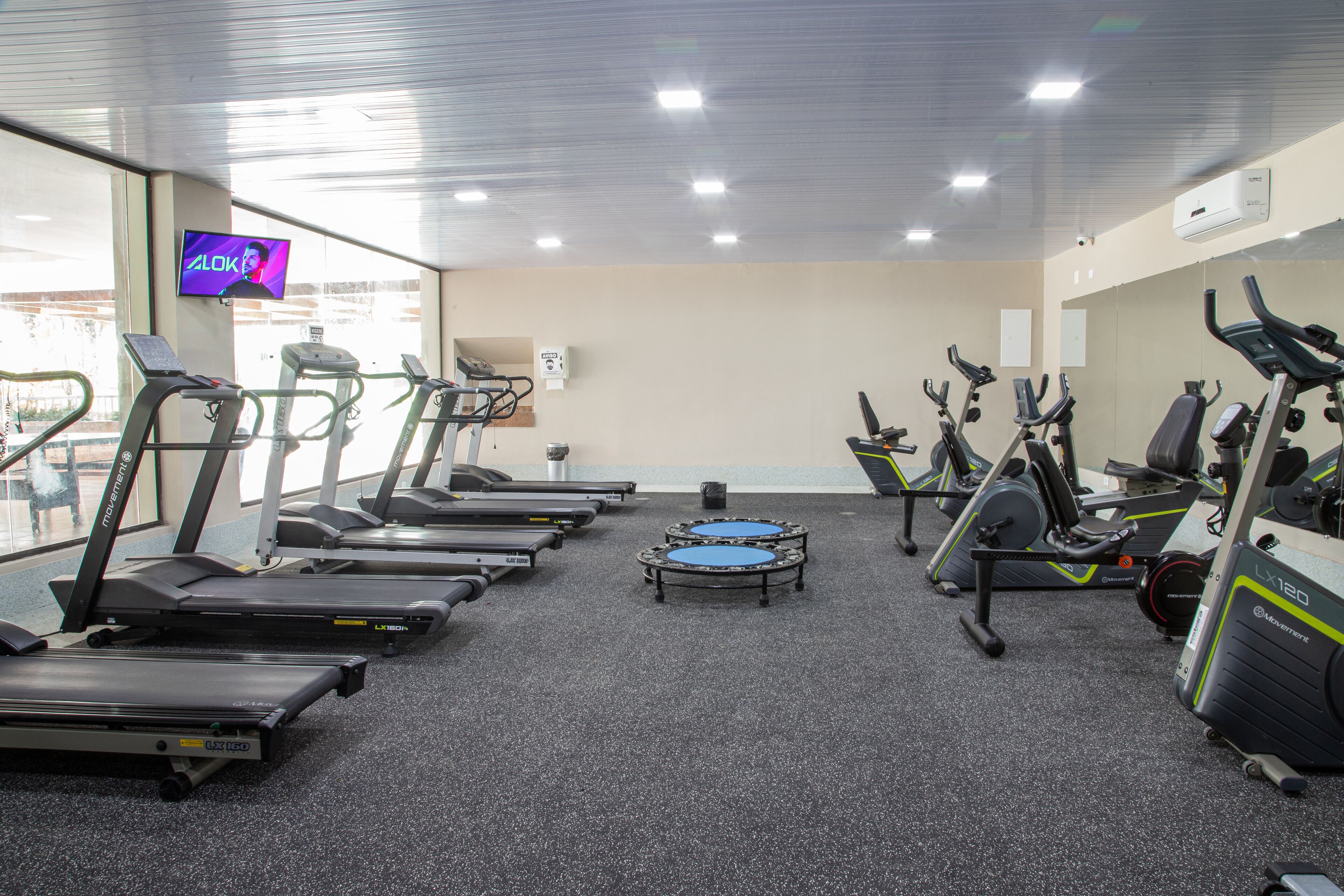 Une salle de sport équipée de tapis de course, de vélos elliptiques et d’un vélo d’appartement.