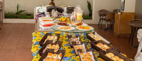 A buffet setup with various food items and beverages, arranged on a table with a floral tablecloth.