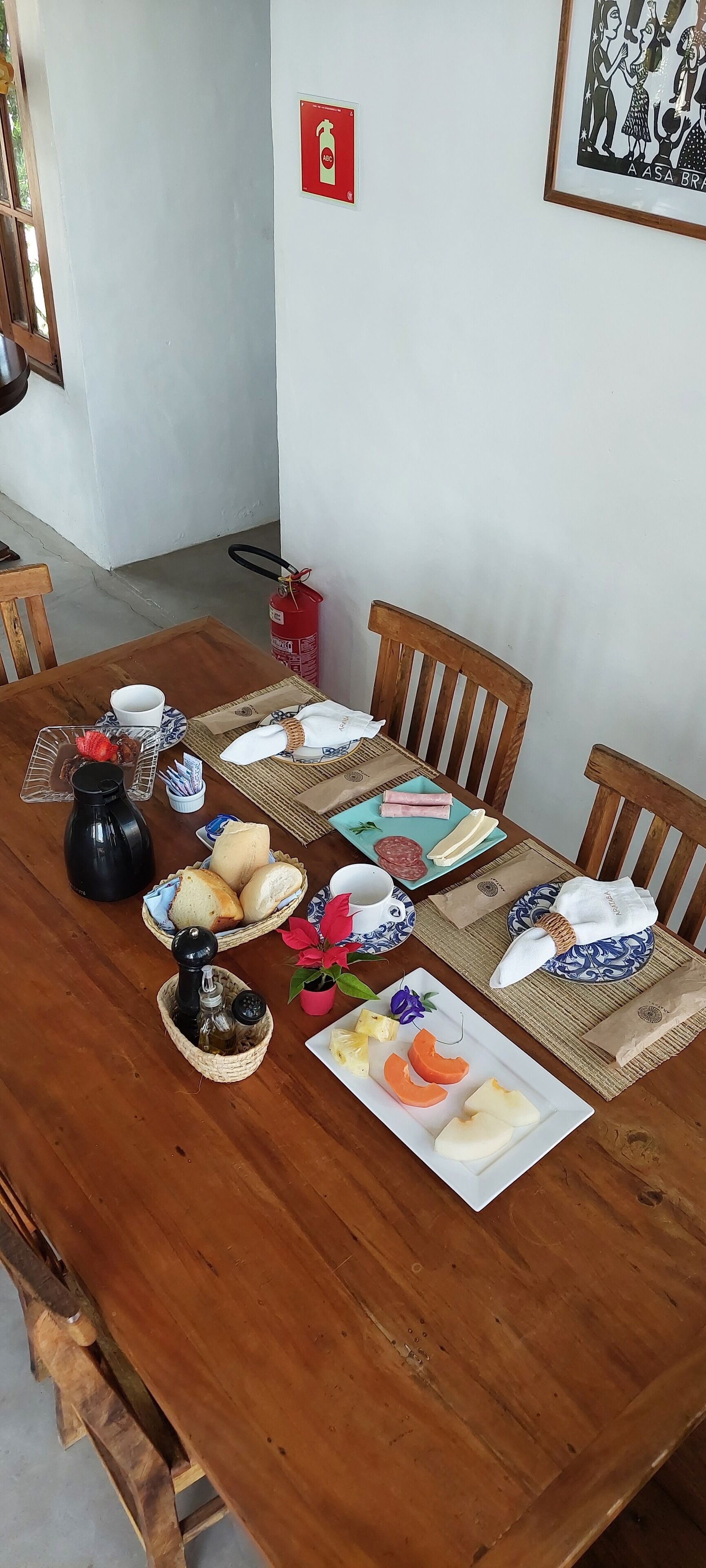 A wooden dining table set with plates, bread, and condiments.