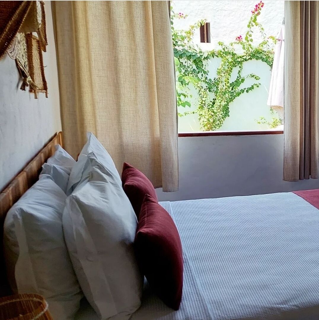 Una habitación con una cama, una ventana con cortinas y vistas a zonas verdes.