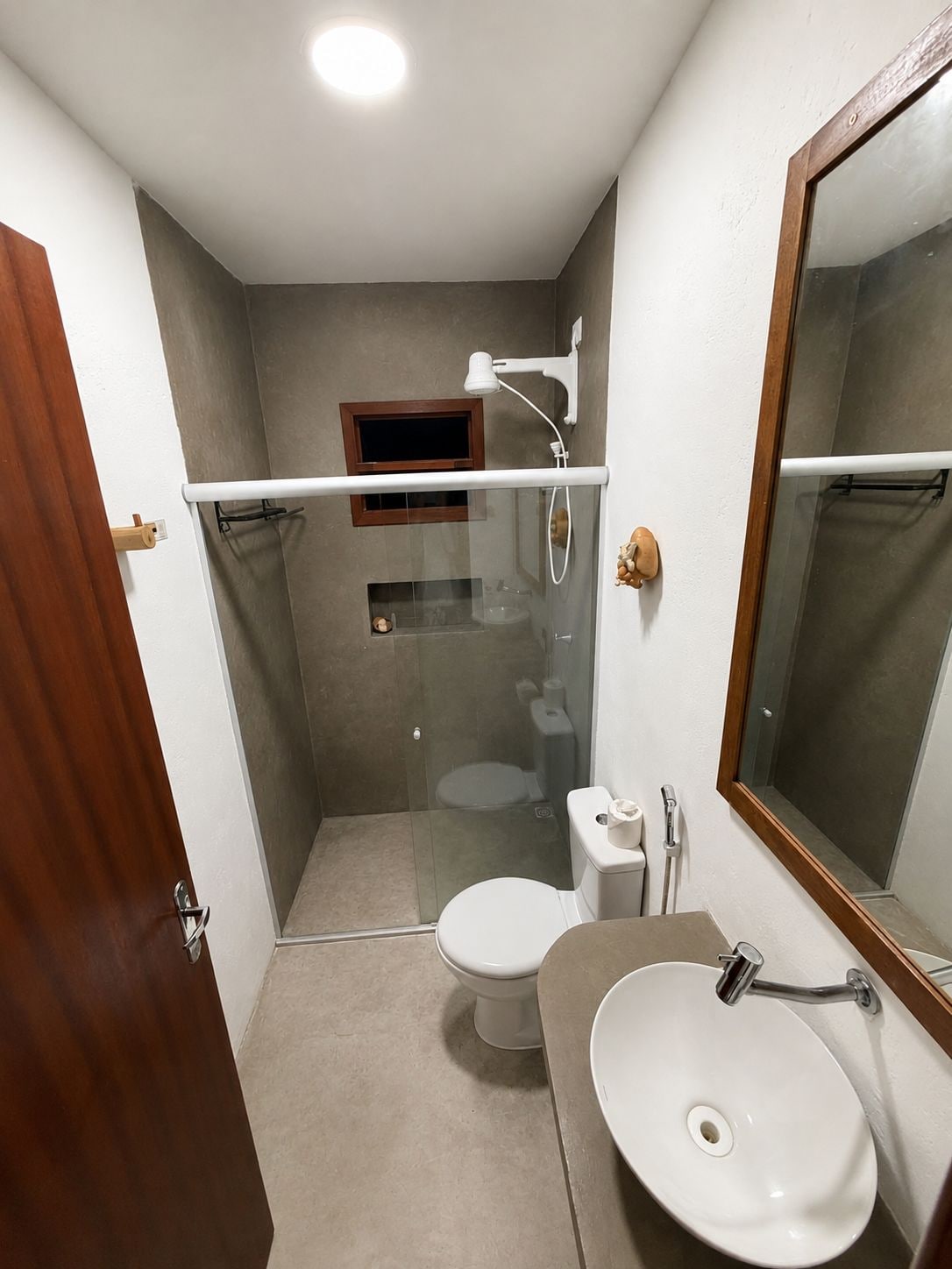 Un baño compacto con ducha envuelta en vidrio, inodoro y lavamanos.