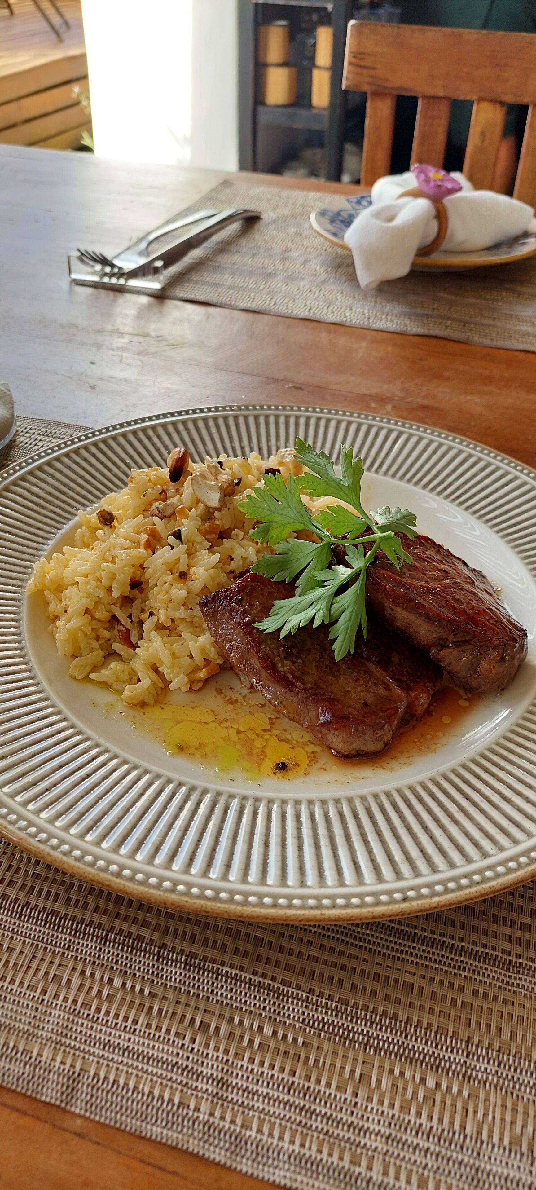 Un plato de comida con arroz, carne y guarnición sobre una mesa.