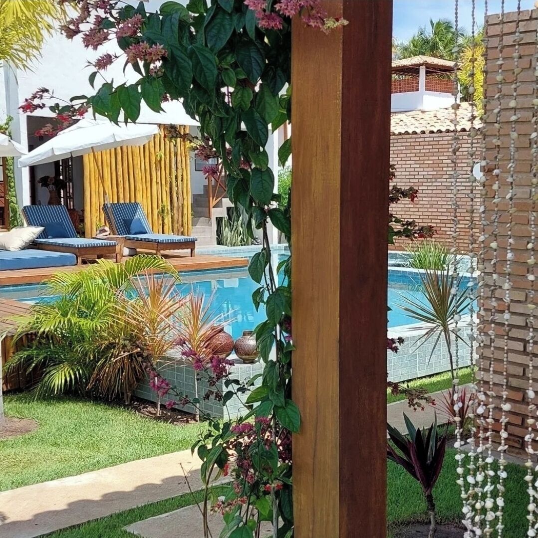 A pool area with lounge chairs, a wooden pergola, and various plants.