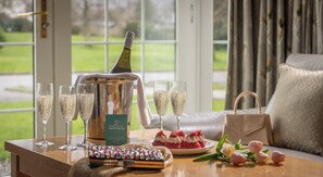 A table with champagne glasses, a bottle, a remote control, and a plate of strawberries. - The Flesk River Apartments (Killarney)