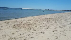 A beach with clear blue water, a sandy shore, and boats in the distance. - Mobil-home Climatisé Dans Camping 4 - Cap-ferret (Lège-Cap-Ferret)