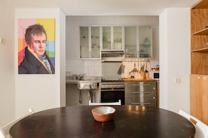 A modern kitchen with white cabinets, stainless steel appliances, and a wooden dining table.