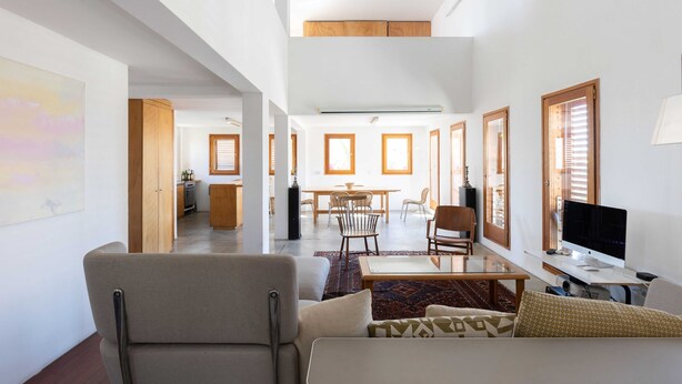 A spacious living area with a sofa, a coffee table, and a TV. There is a dining area with a table and chairs, and a kitchen in the background. - Secret Garden by TLV2RENT (Tel Aviv)