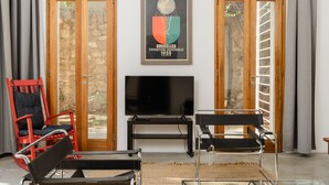 A modern living room with a television, two chairs, a glass coffee table, and a framed picture on the wall. - Secret Garden by TLV2RENT (Tel Aviv)