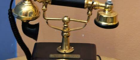 A vintage rotary dial telephone on a wooden table.