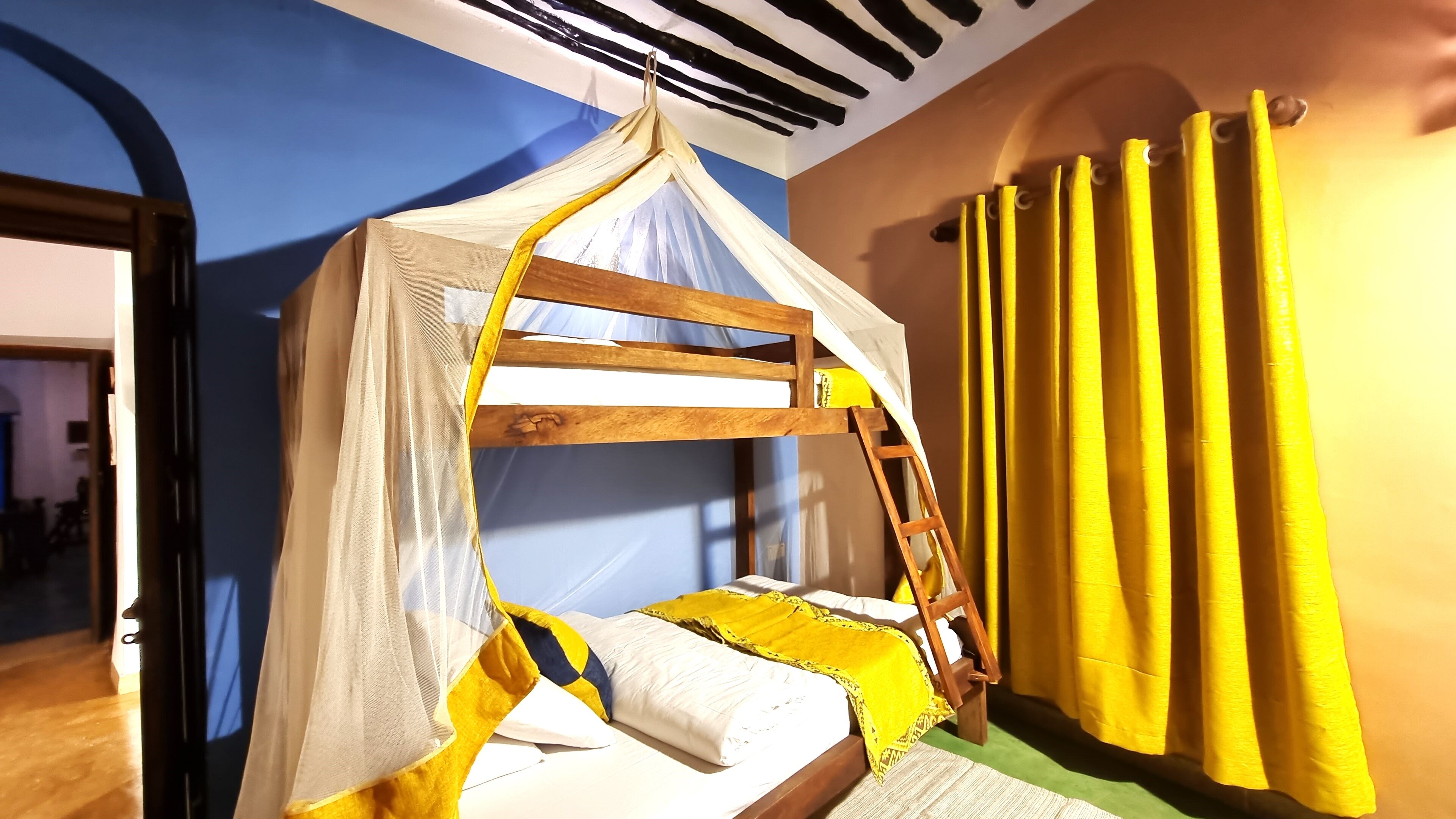 A bunk bed with a canopy, a ladder, and yellow curtains.