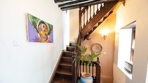 Una escalera con barandillas de madera, una planta en maceta y un aplique en la pared.