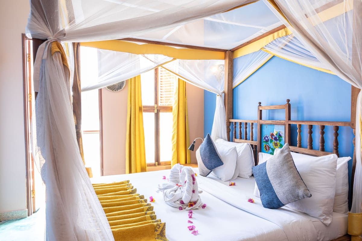 Een bed met witte lakens, een houten hoofdbord en een blauwe muur.