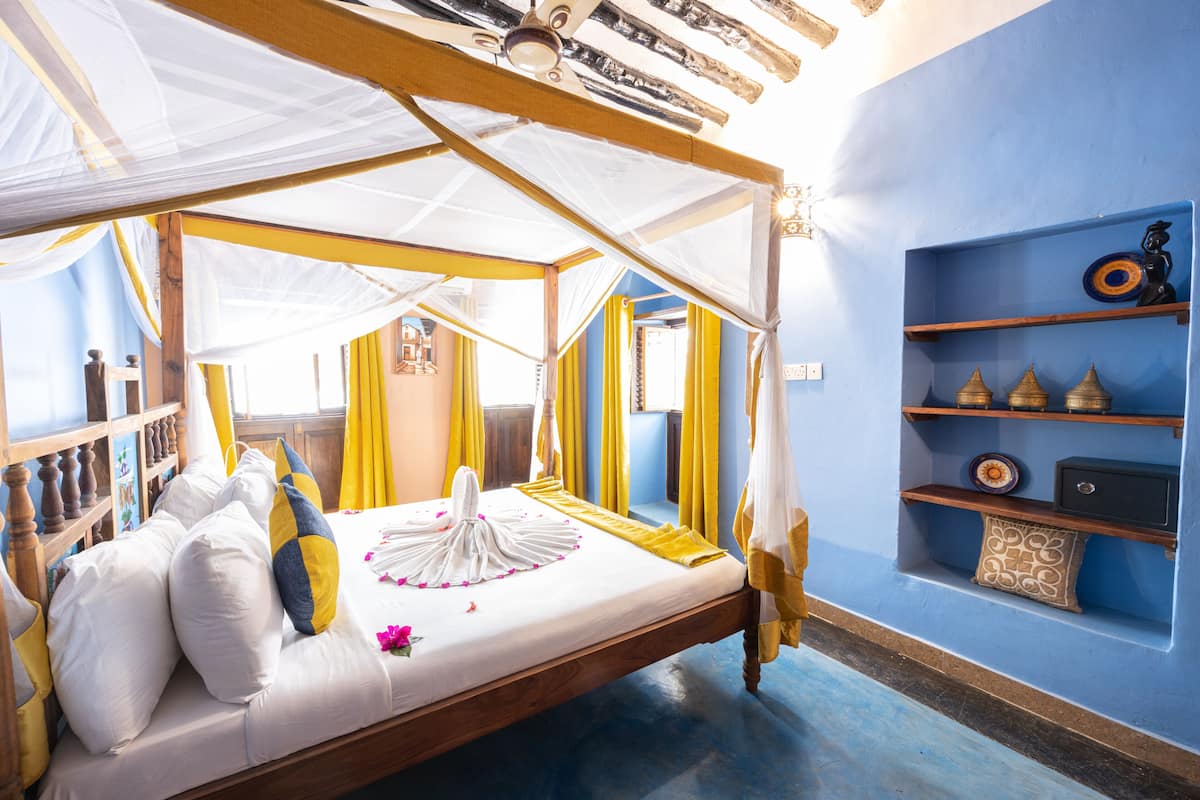 Een hemelbed met een baldakijn, een nachtkastje en een plank met decoratieve objecten.