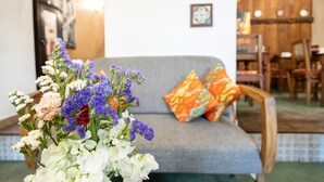 Una sala de estar con un sofá gris, cojines coloridos y un arreglo floral.