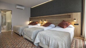Habitación de hotel con tres camas, ducha y piso estampado.