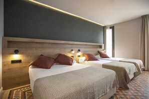 Une chambre d’hôtel avec deux lits, une tête de lit en bois, des lampes fixées au mur et un sol à motifs.