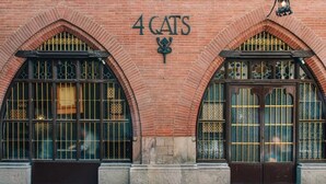 Un edificio de ladrillo con ventanas arqueadas y un letrero que dice '4 CATS'.