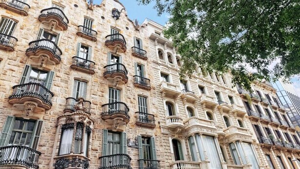Un edificio histórico con balcones ornamentados y ventanas amplias.