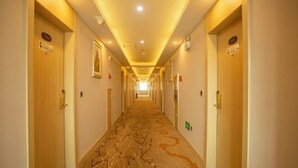 Um corredor de hotel com portas de madeira, piso carpete e iluminação embutida.