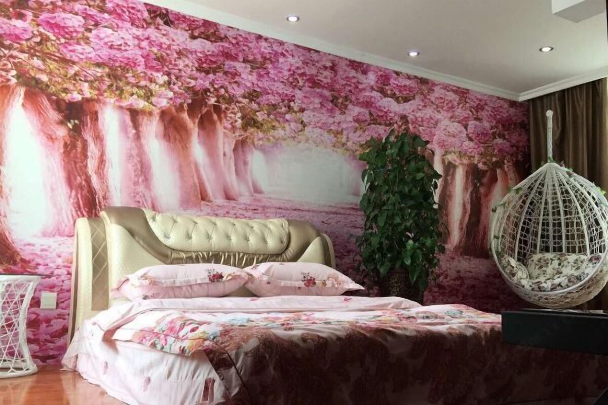 Een slaapkamer met een grote bloemenmuur, een gestapeld hoofdbord, een hangstoel en een potplant.