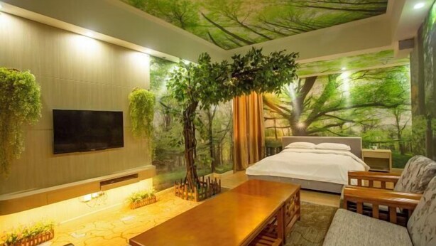 Quarto com cama, televisão na parede, mesa de madeira e sofá.