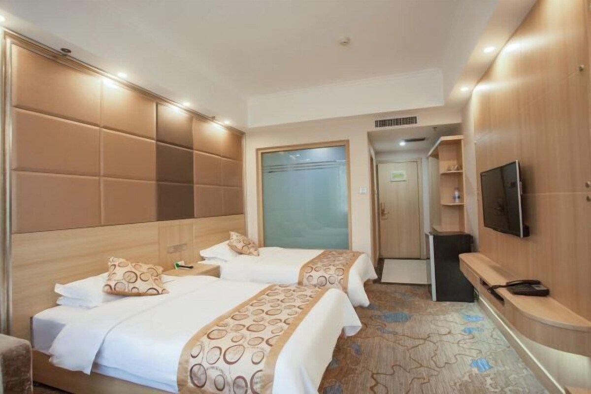 Een hotelkamer met twee bedden, een televisie, een bureau en een kledingkast.