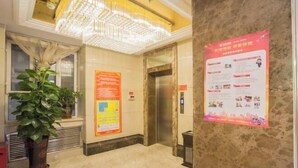 Um hall de entrada com piso de mármore, um grande candelabro, um elevador e cartazes informativos nas paredes.