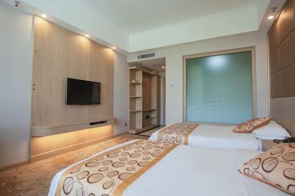 Ein Hotelzimmer mit zwei Betten, einem an der Wand befestigten Fernseher, einem begehbaren Kleiderschrank und einem großen Fenster mit Aussicht.