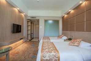 Ein Hotelzimmer mit Bett, Nachttisch, Fernseher und Blick nach draußen.