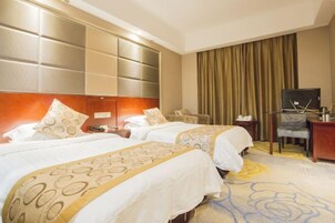 Habitación de hotel con dos camas, televisión, escritorio y una silla.