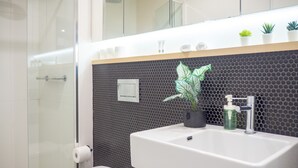 A modern bathroom with a white sink, a mirror, and a potted plant. - Classy & Spacious 2 Bedroom, 2 Bathroom (En Suite) (Elsternwick)