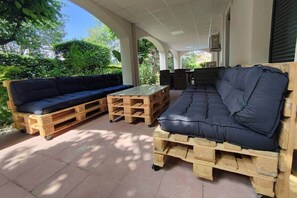 A covered outdoor seating area with a sofa and a table made from wooden pallets. - Magnificent villa with swimming pool and gym (Aubenas)