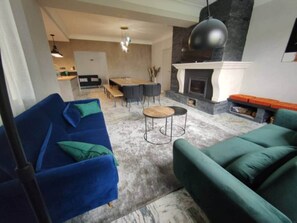 A living room with a blue sofa, a green sofa, a round coffee table, and a fireplace. - Magnificent villa with swimming pool and gym (Aubenas)
