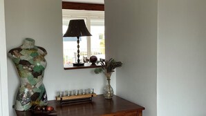 Een houten console tafel met een spiegel, een decoratieve vaas en een klein plankje met kaarsen.