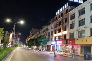 A nighttime street view with illuminated storefronts and a clear road.