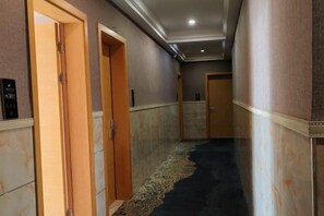 A hallway with wooden doors, a patterned carpet, and a marble floor.