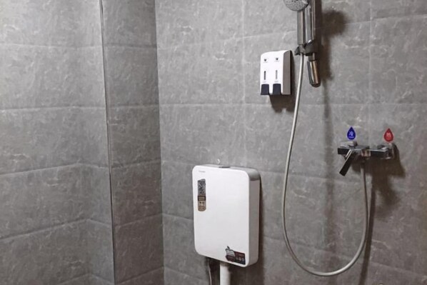 A shower area with a control panel and a handheld showerhead.