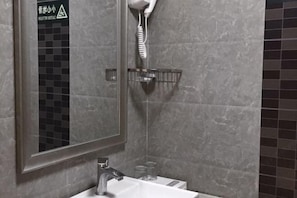 A bathroom with a mirror, sink, and a hairdryer mounted on the wall.