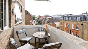A balcony with a table, two chairs, and a bottle of champagne.